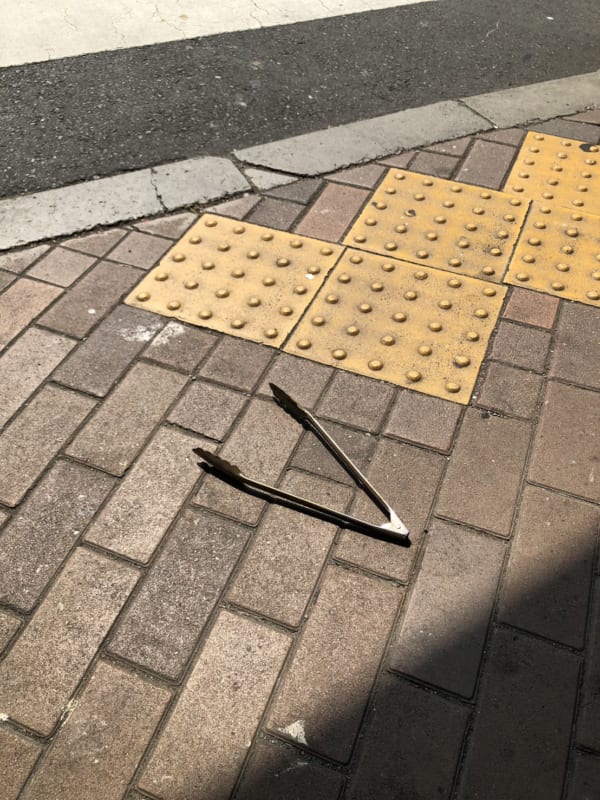 都内の路上にて発見したトング。焼肉店で使い、手にもったまま店を出てしまった、うっかりさんがいたのだろうか……。(写真/ダーシマ)