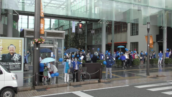 新田氏の演説を待ち構える支援者。青い風船や「新田」と書かれた青い札を持ち盛り上げる。(撮影/畠山理仁)