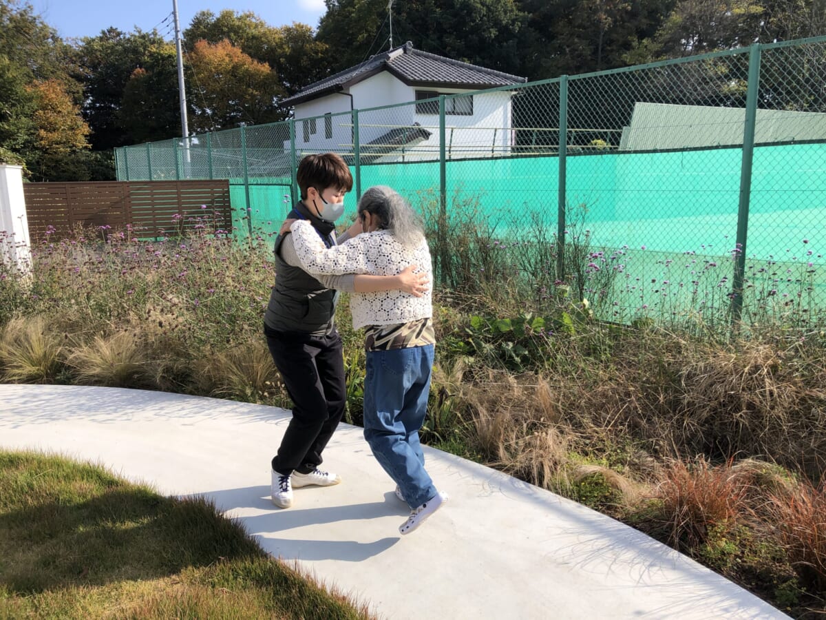 中庭で利用者の方から社交ダンスを教わる白神さん