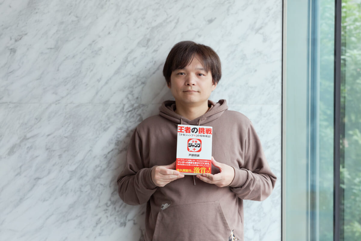 できたばかりの新刊を持つ著者。帯には佐久間宣行(テレビプロデューサー)の熱い推薦文が。