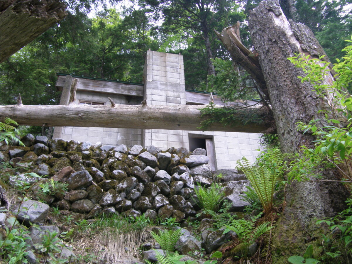手前の倒木で少し見えにくいアングルだが、滝谷避難小屋の外観。至近距離に川があり、増水に備えて高台にある