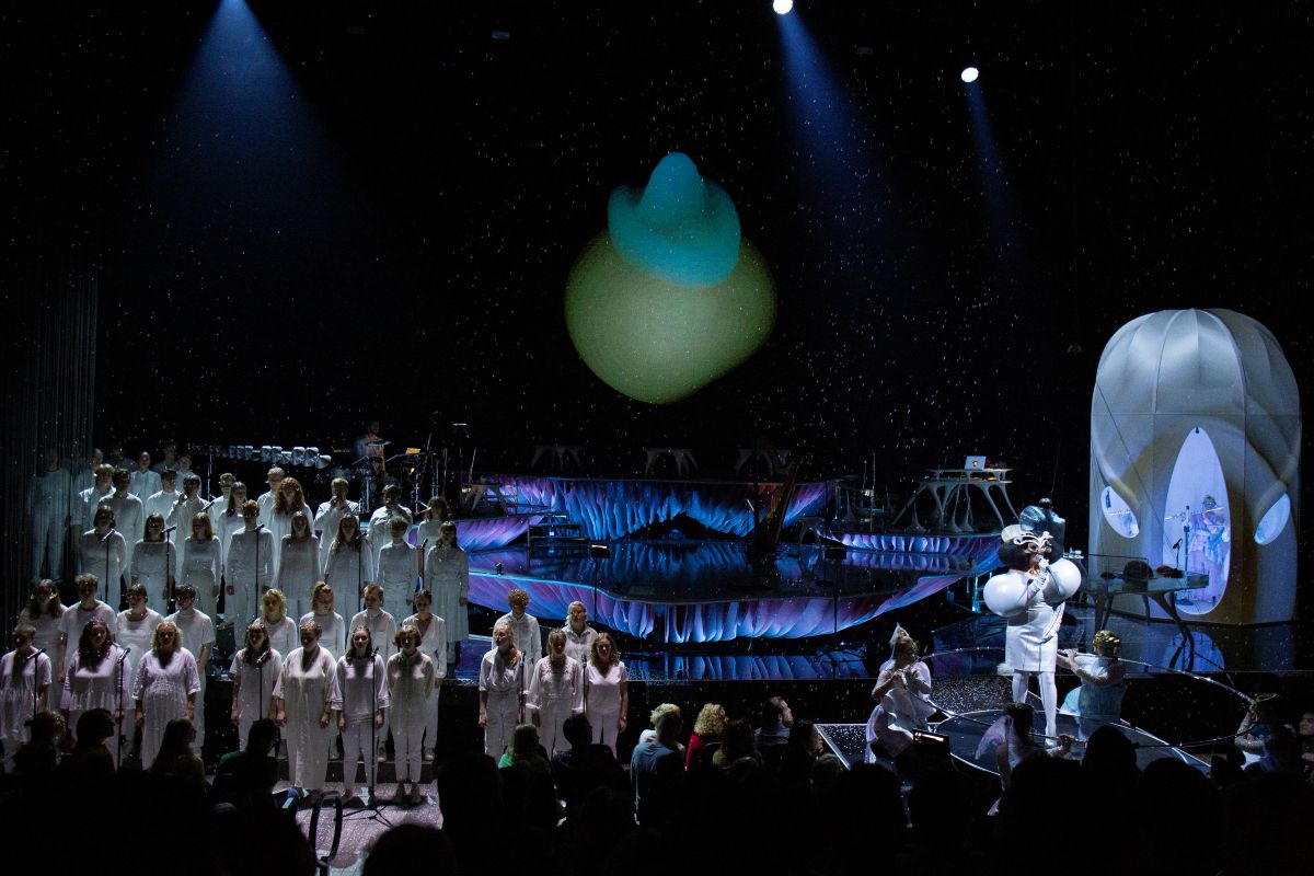 左側に男女混成合唱団、右は特注のフルートの輪の中で歌うビョーク 　Photo: Santiago Felipe