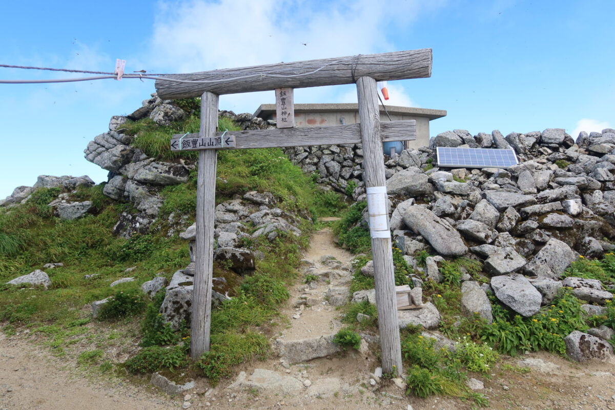 登山道脇に立つ、飯豊山神社奥宮の鳥居。その奥に周囲を石垣で守った奥宮の建物がある