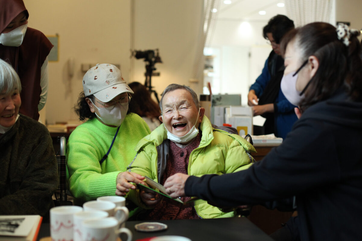 介護施設からの訪問。アルバムをめくりながら話が弾む。撮影：仲田絵美　提供：水戸芸術館