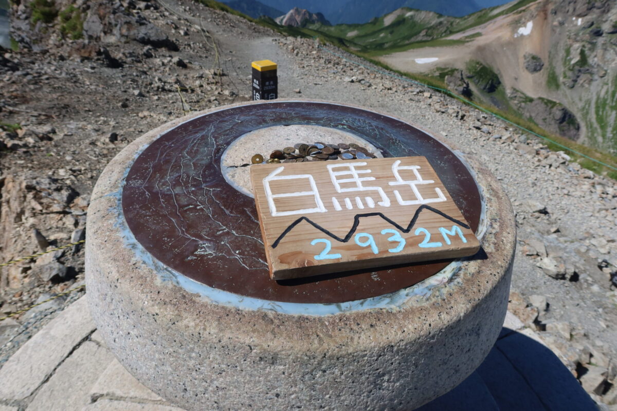 白馬岳山頂の風景指示版。茶色の銅板の上に周囲に見える山の名前が書かれている