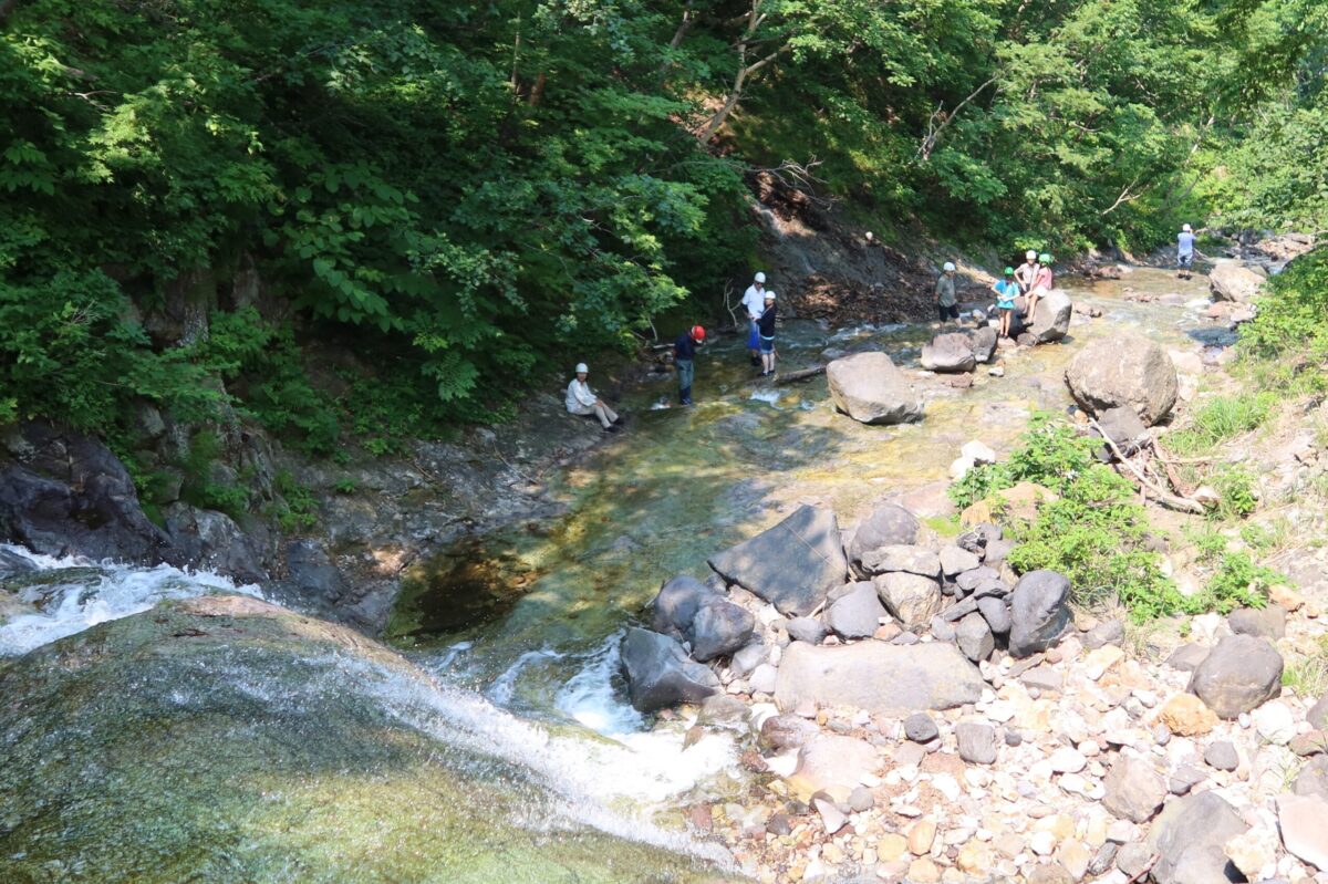 思い思いに沢を楽しむ登山者を「3の滝」の上から見下ろす。事前予約に基づいて多くの人が同じ時間に登り始めるため、秘境の温泉といえども、沢の中は意外と賑やかだ