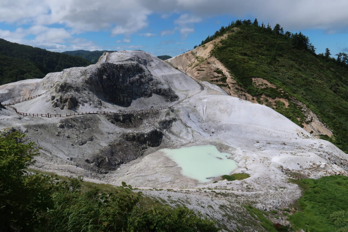 グレーの土砂が作り出す起伏のなかに、薄いグリーンの池が眠る川原毛地獄の中心部